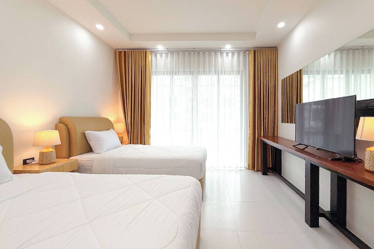 A hotel room with two beds, a TV, and a desk.