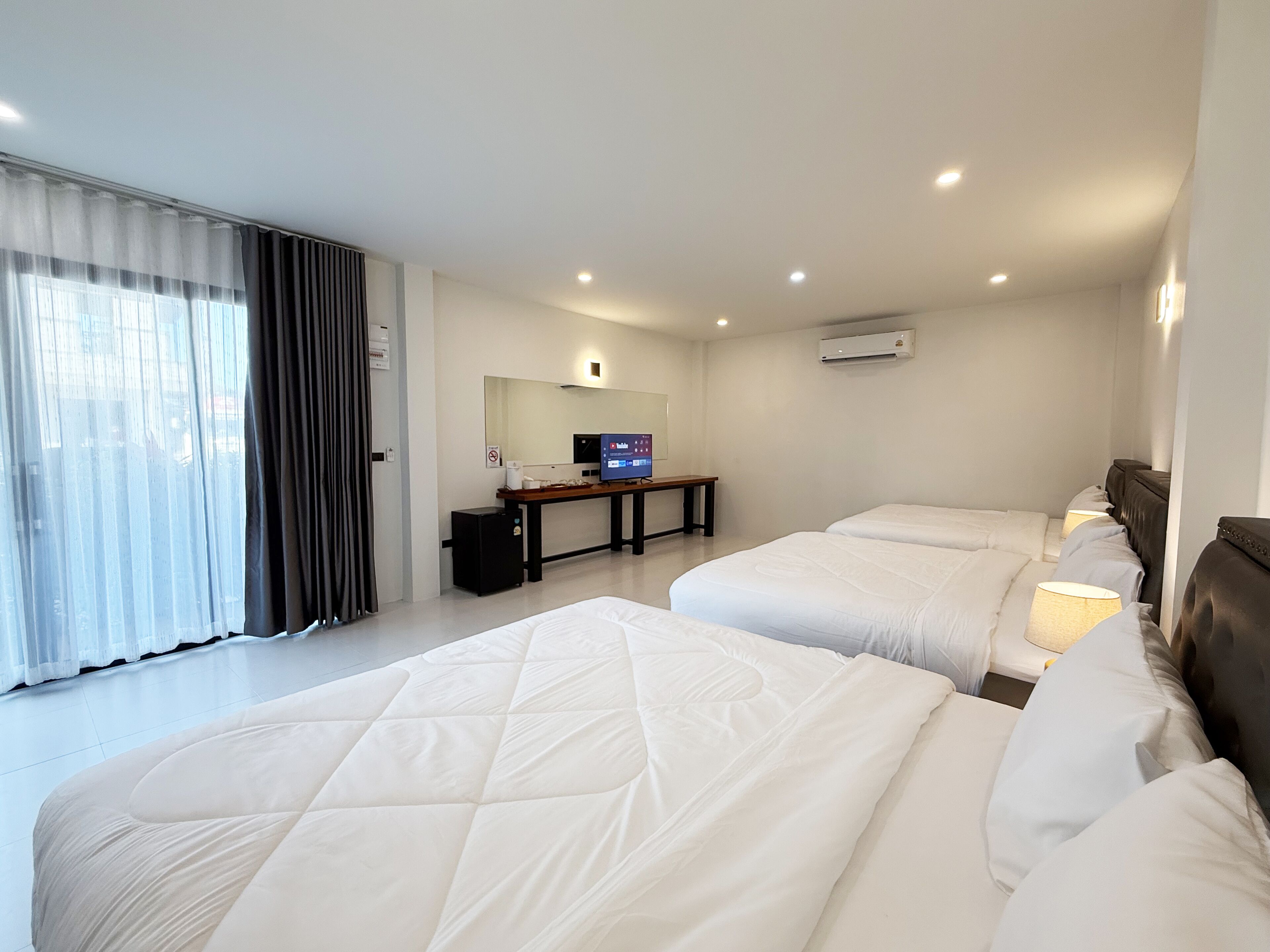 Habitación de hotel con dos camas, un escritorio, un televisor y aire acondicionado.