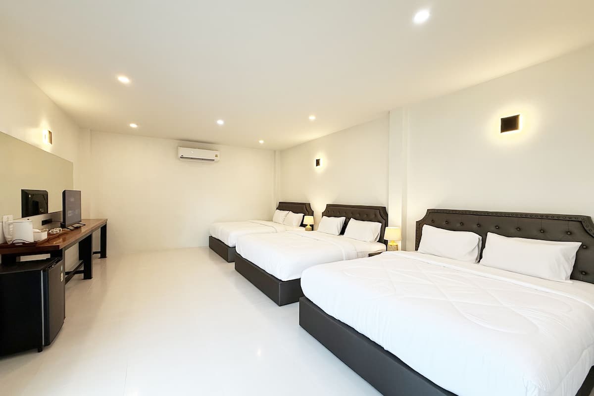 A hotel room with two beds, a desk with a computer, and a flat-screen TV.