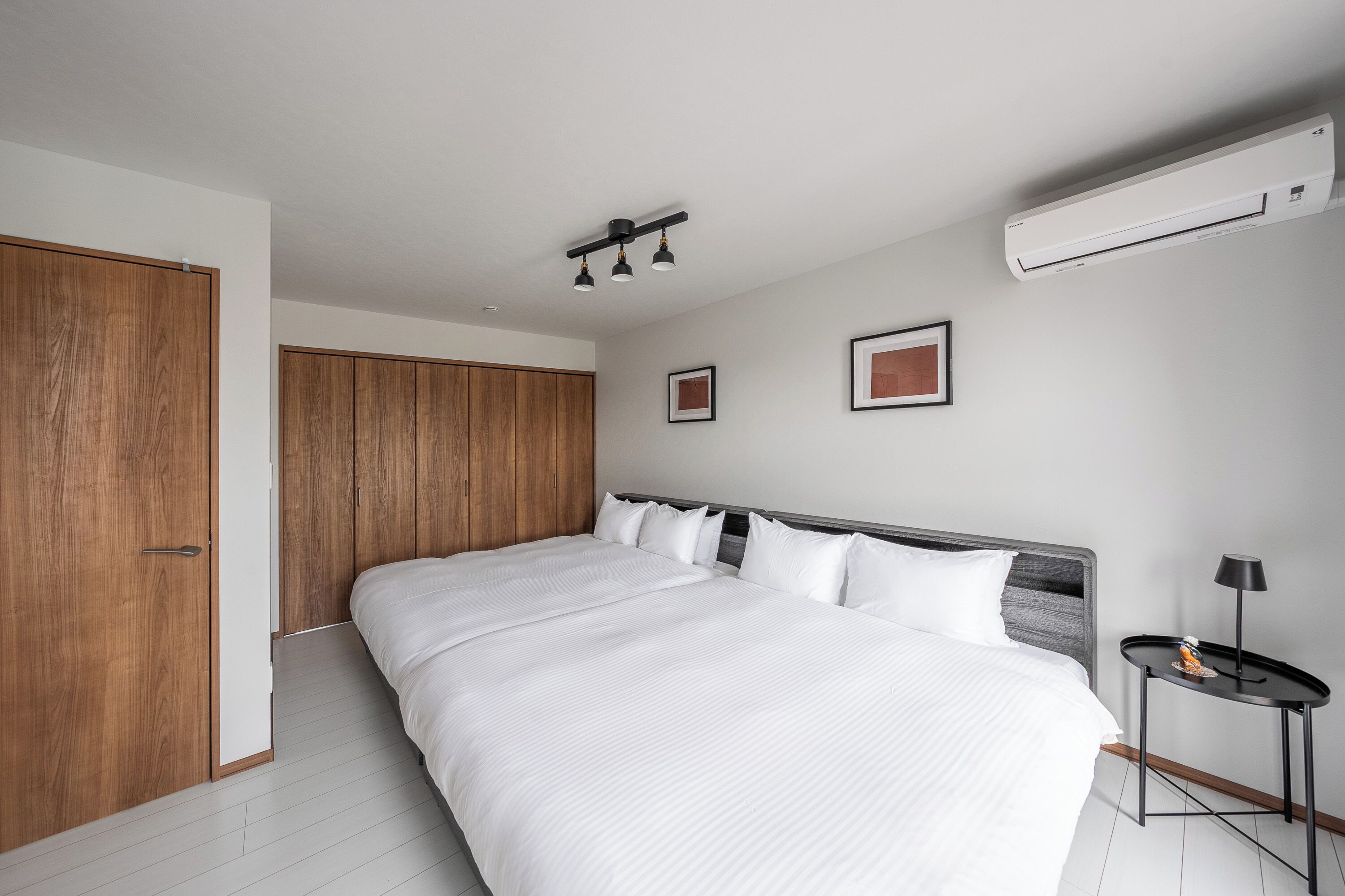 Un dormitorio moderno con una cama grande, un armario de madera y una mesita de noche.
