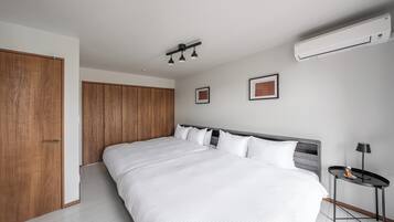 Un dormitorio moderno con una cama grande, un armario de madera y una mesita de noche.