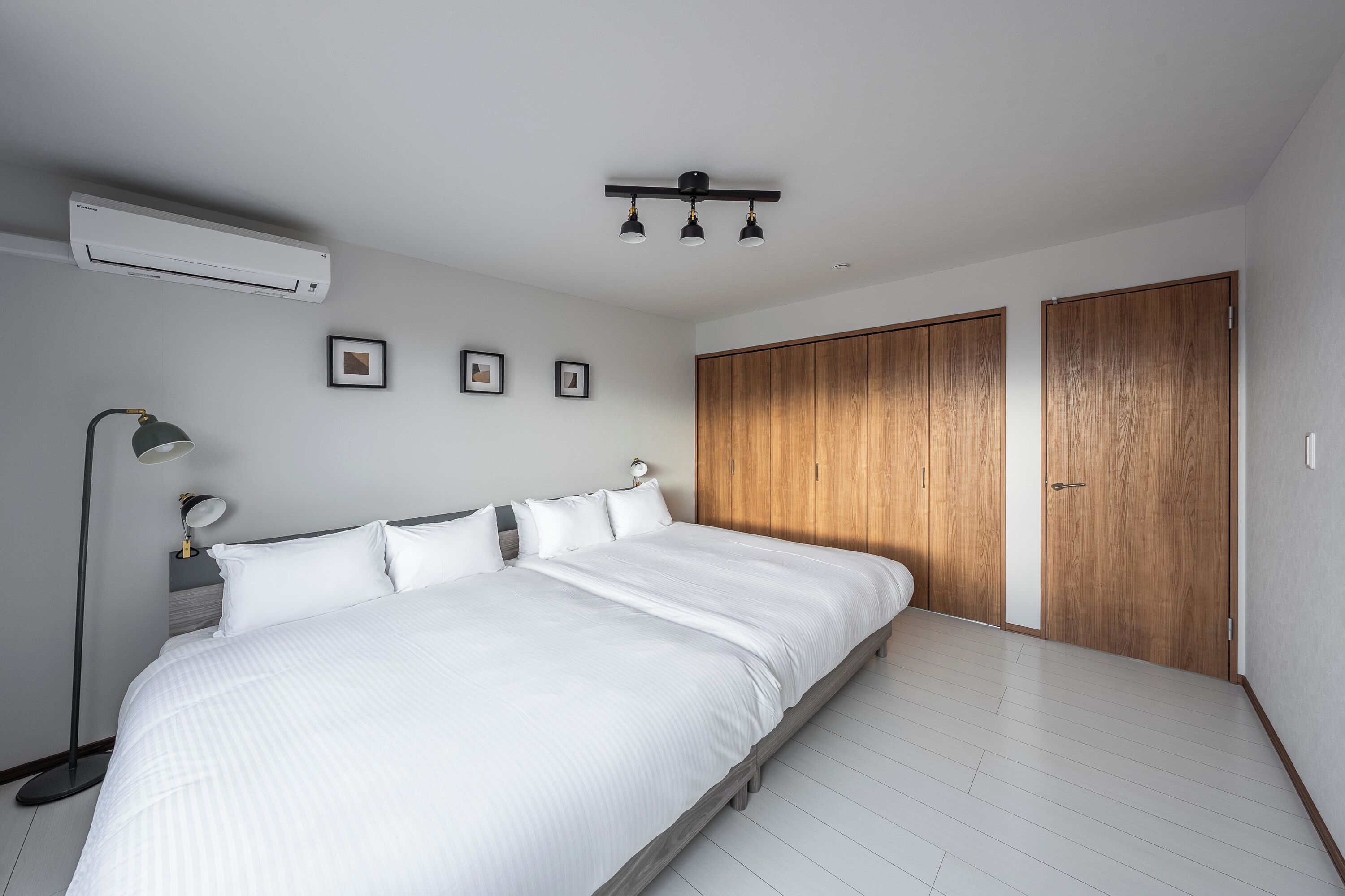 Un dormitorio con una cama grande, una lámpara de noche, una lámpara de techo y armarios de madera.
