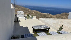 Una terraza con mesa y sillas, una planta en maceta y vista al mar.