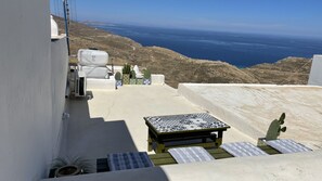 A terrace with a table and chairs, a potted plant, and a view of the sea. - Camaraki Green House Serifos , (Serifos)