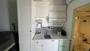 Una kitchenette compacta con armarios blancos, un salpicadero estampado y una pequeña encimera.