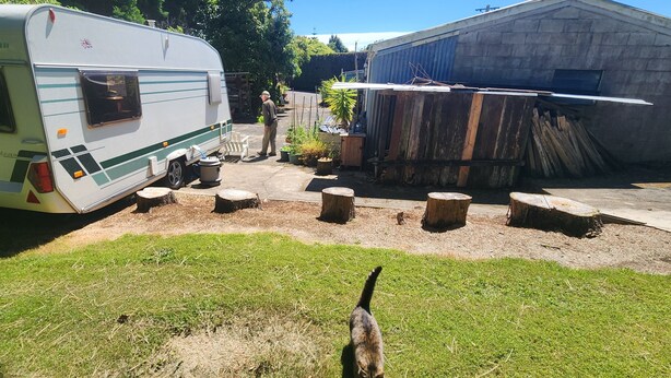 A recreational vehicle (RV) parked in a backyard with a wooden deck and a shed.