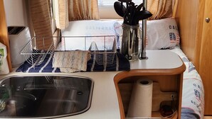 A compact kitchen area with a sink, stove, and storage shelves.