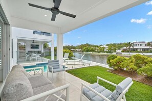Une terrasse extérieure moderne dotée d’une piscine, d’un espace salon et offrant une vue sur un lac et la végétation environnante.