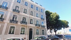 Un immeuble à plusieurs étages, doté de façades à motifs, d’une porte verte et de balcons avec des garde-corps noirs.