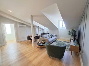 Een moderne woonkamer met een hoge plafond, een bank, een salontafel en een eethoek.