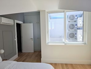 A bedroom with a bed, a wardrobe, and a window with air conditioning units. - Apartment 503 • Lisbon • 1 bedroom • Elevator • AC (Lisbon)