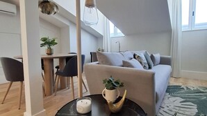 Un appartement moderne de style « loft », comprenant un coin repas, un ensemble de canapés, une table basse et une grande fenêtre laissant entrer la lumière naturelle.