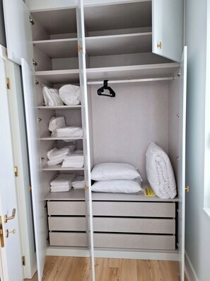 A walk-in closet with multiple shelves, drawers, and hanging space, featuring a minimalist design and light wood flooring. - Apartment 503 • Lisbon • 1 bedroom • Elevator • AC (Lisbon)