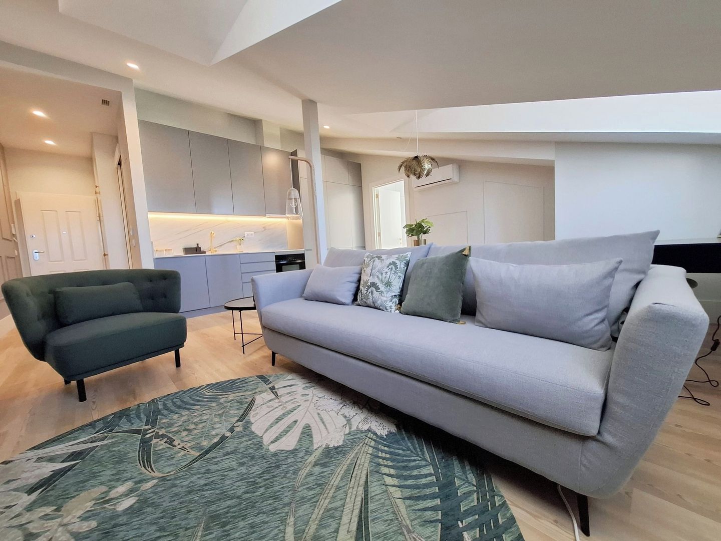 A modern living room with a sofa, armchair, and a patterned rug.