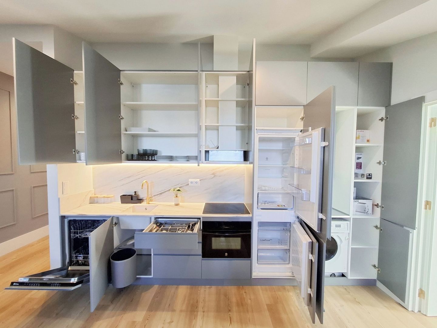 A compact kitchen with built-in appliances, open shelving, and a dishwasher.