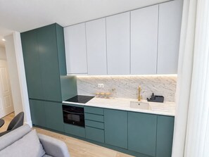 Eine moderne Küche mit türkis-blauen Schränken, einer weißen Arbeitsplatte und einem eingebauten Backofen.
