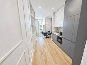 Une cuisine moderne avec des meubles gris, un plancher en bois et un coin repas comprenant une table et des chaises.