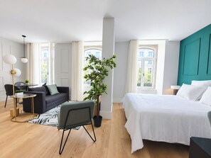 A modern hotel room with a bed, a sofa, a small table, and a potted plant. - Studio 401 • Lisbon • Elevator • AC • Wi-Fi (Lisbon)