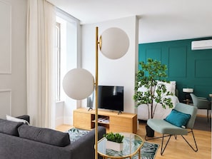 A modern living room with a sofa, a coffee table, a TV, a plant, and a teal accent wall. - Studio 401 • Lisbon • Elevator • AC • Wi-Fi (Lisbon)
