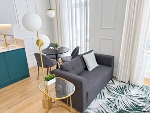 Una sala moderna con un sofá gris, una mesa de centro de vidrio y una mesa de comedor redonda con sillas.