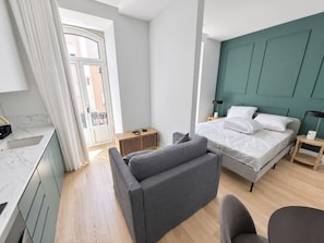 A modern bedroom with a bed, bedside tables, a chair, and a view of the outside. - Studio 202 • Lisbon • Balcony • Elevator • A/C (Lisbon)