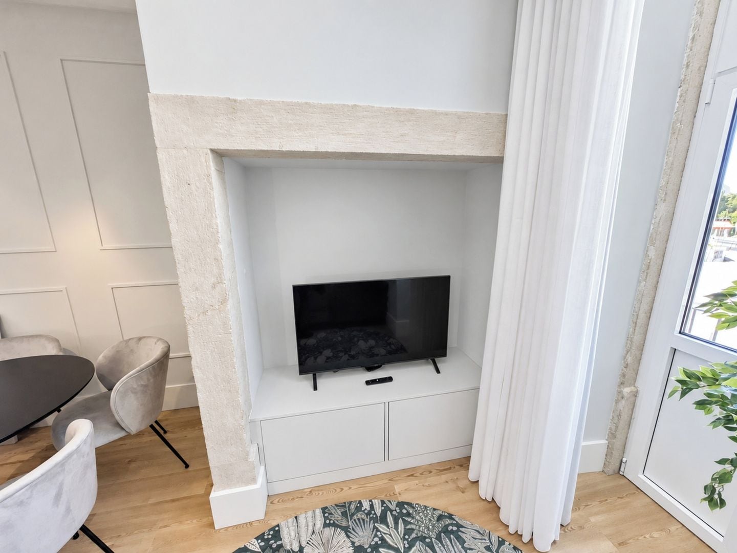 En moderne stue med pejs, et fladskærms-tv, et spisebord med stole og udsigt til det fri gennem et vindue.