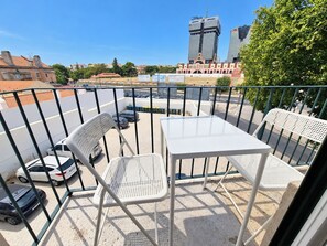 A balcony with two white metal chairs and a table, overlooking a parking area and buildings. - Apartment 307 • Lisbon • 1 bedroom • Balcony • AC (Lisbon)