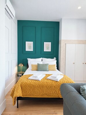 Comfortable double bed with fresh linens, built-in storage and a bold teal backdrop - Studio 205 Lisbon • Balcony • Elevator • AC • WiFi (Lisbon)