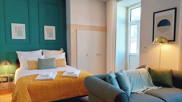 A hotel room with a bed, a sofa, teal walls, and framed artwork. - Studio 205 Lisbon • Balcony • Elevator • AC • WiFi (Lisbon)