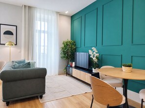 A modern living room with a sofa, a dining table with chairs, a TV, and a plant. - Studio 205 Lisbon • Balcony • Elevator • AC • WiFi (Lisbon)