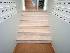 Eine Treppe führt zu einer Zwischenebene mit einer Reihe von Briefkästen an beiden Seiten.