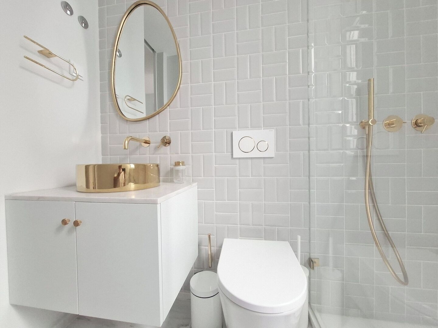 A modern bathroom with a white vanity, gold fixtures, and a large mirror.