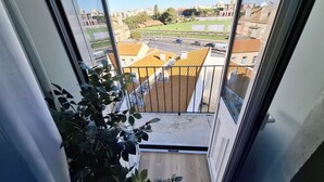 Un balcón con vista a un paisaje urbano, incluyendo edificios y una carretera.