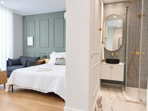 A modern hotel room with a bed, bedside table, and a bathroom with a shower and sink. - Studio 302 Lisbon • Balcony • Elevator • AC • WiFi (Lisbon)