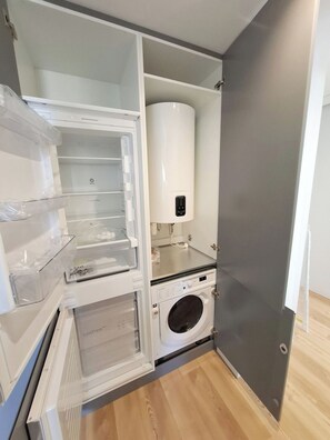 A compact kitchen with a built-in washing machine, a refrigerator with multiple compartments, and a microwave. - Apartment 501 • Lisbon • 1 bedroom • Elevator • AC (Lisbon)