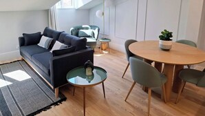 Ein modernes Wohnzimmer mit einem dunklen Sofa, einem runden Holzesstisch und einem kleinen Beistelltisch.