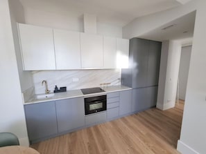 A modern kitchen with white cabinets, a marble backsplash, and a built-in oven. - Apartment 501 • Lisbon • 1 bedroom • Elevator • AC (Lisbon)