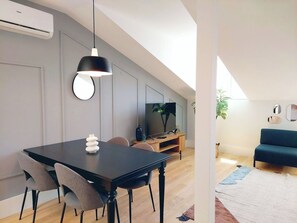 Ein moderner Wohnbereich mit Essplatz, Fernseher und Sofa.