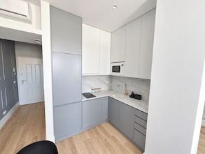 A compact kitchen with grey cabinets, a marble countertop, a built-in microwave, and a sink with a gold faucet. - Studio 305 Lisbon • Balcony • Elevator • AC • WiFi (Lisbon)