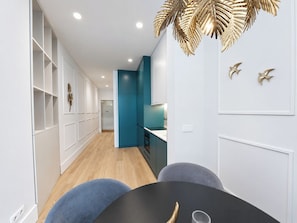 A modern interior with a dining area featuring a black table and blue chairs, a kitchen with teal cabinets, and a decorative gold leaf ceiling. - Apartment 207 • Lisbon • 1 bedroom • Balcony • AC (Lisbon)
