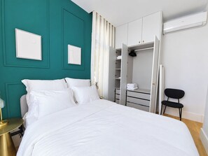 A bedroom with a bed, a wardrobe, a chair, and a bedside table. - Apartment 207 • Lisbon • 1 bedroom • Balcony • AC (Lisbon)