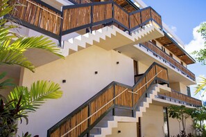 Ein mehrstöckiges Gebäude mit modernem Design, das eine Treppe mit Holzgeländern und einer weißen Fassade zeigt.