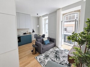 A modern apartment with a kitchen, a grey sofa, a patterned rug, and a balcony with a view. - Studio 201 • Lisbon • Balcony • Elevator • WiFi (Lisbon)