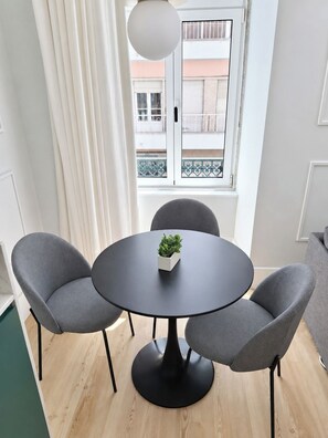 A modern dining area with a round table, two grey chairs, and a small potted plant. - Studio 201 • Lisbon • Balcony • Elevator • WiFi (Lisbon)