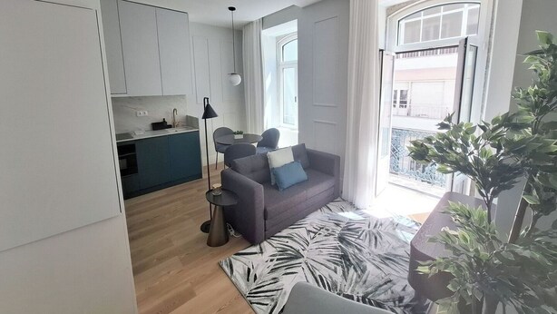 A modern apartment with a kitchen, dining area, and living room. It features a large window with a view of the city, a potted plant, and a patterned rug. - Studio 201 • Lisbon • Balcony • Elevator • AC (Lisbon)