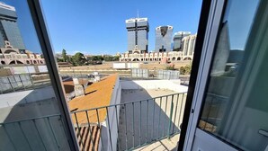 Parveke, josta avautuu näkymä kaupunkimaisemaan, mukaan lukien modernit rakennukset ja kirkas taivas.