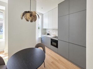 A modern kitchen with grey cabinets, a black dining table, and a pendant light with a leaf design. - Apartment 106 • Lisbon • 1 bedroom • Elevator • AC (Lisboa)