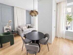 A modern living room with a grey sofa, a round dining table with grey chairs, a floor lamp, and a potted plant by the window. - Apartment 106 • Lisbon • 1 bedroom • Elevator • AC (Lisboa)