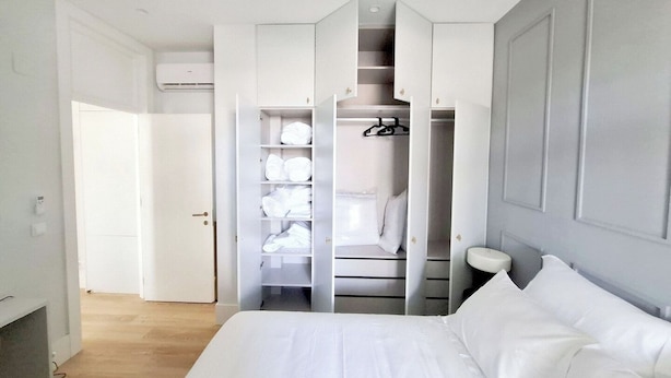 Une chambre à coucher comprenant un lit, une armoire avec plusieurs étagères et des toilettes.