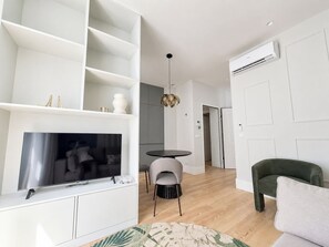 A modern living room with a flat-screen TV, a round dining table, and two chairs. - Apartment 106 • Lisbon • 1 bedroom • Elevator • AC (Lisboa)